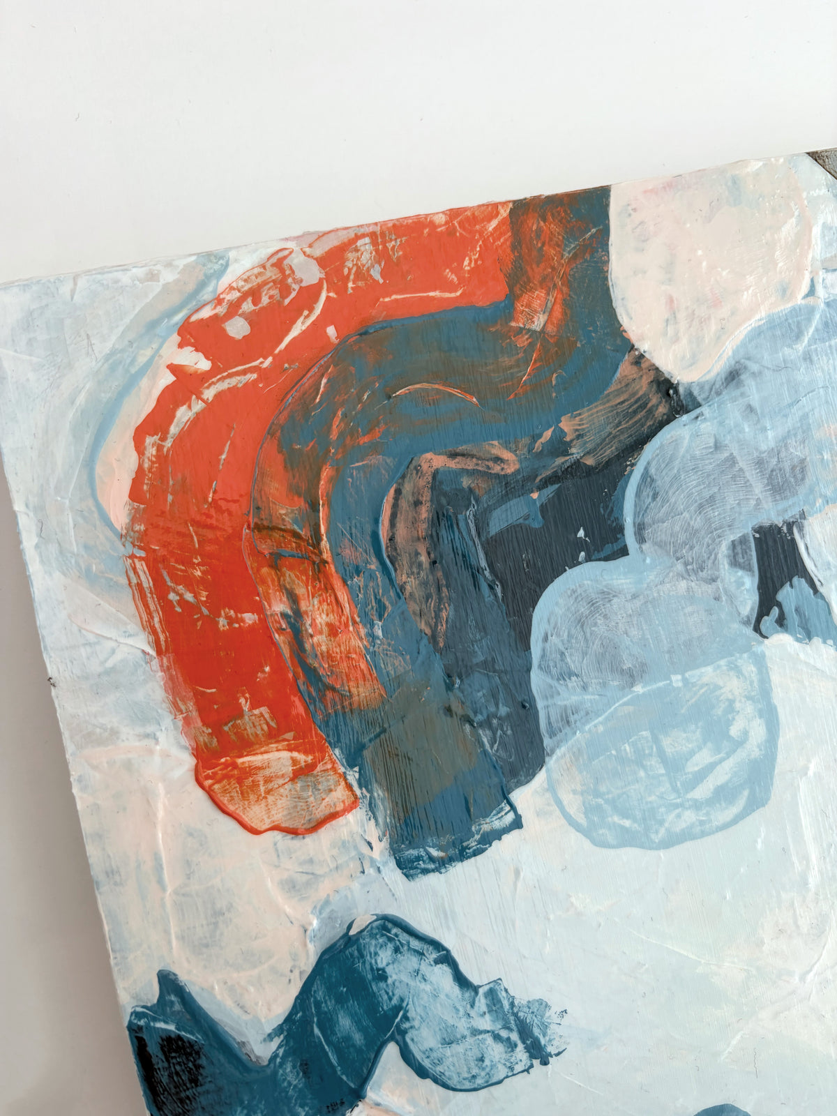 Abstract panel painting with thick impasto brushstrokes in orange, blue, and light blue on a white background.