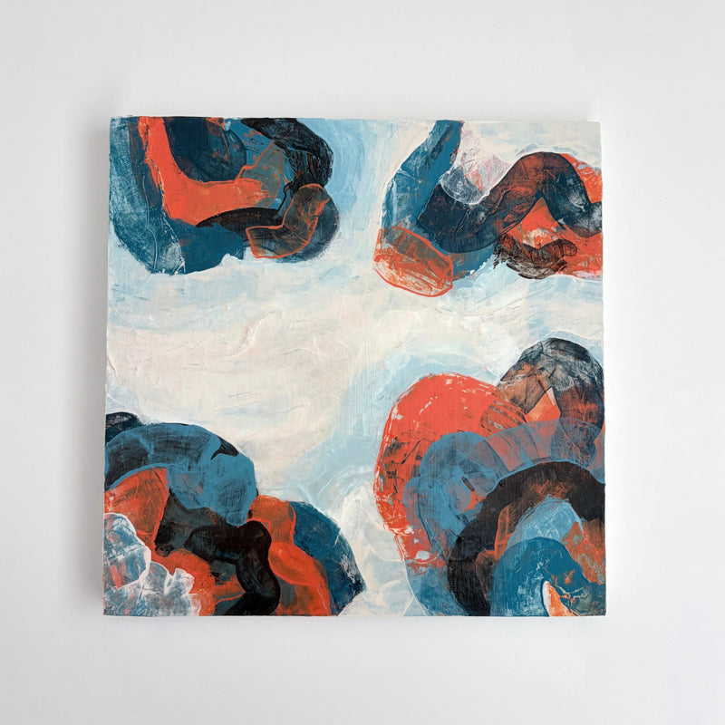 An abstract panel painting featuring organic, flowing shapes in vibrant red-orange, deep blue, and black over a textured off-white background, displayed on a neutral light gray wall.