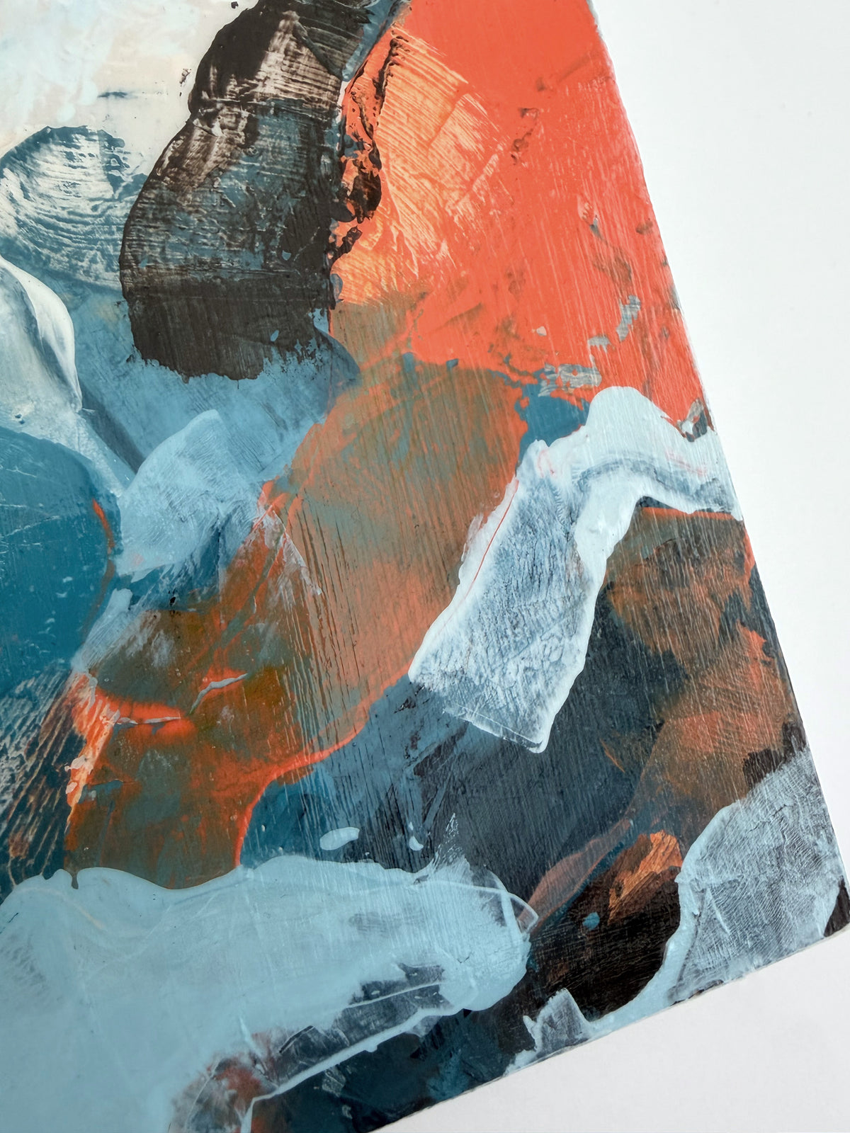 Abstract panel painting with thick textured brushstrokes in orange, blue, dark brown, and off-white, shown at an angle on a white background.