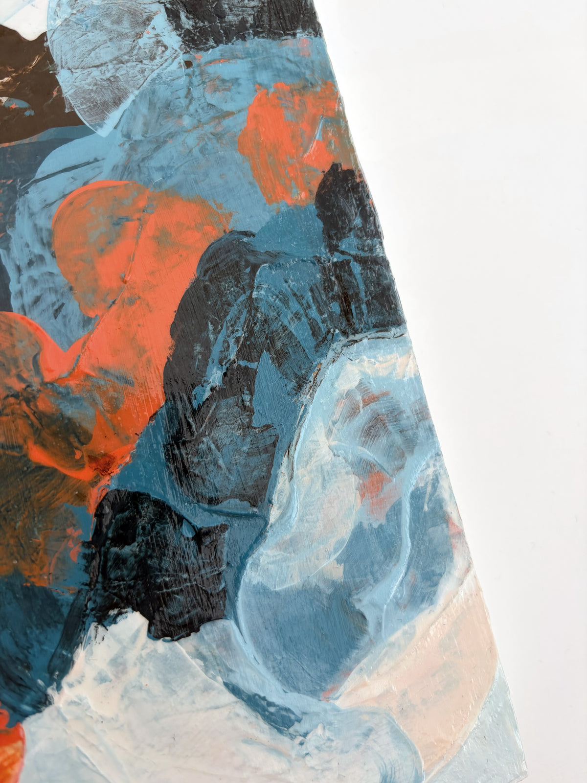 Abstract painting with thick textured brushstrokes in blue, orange, brown, white, and beige, shown with a diagonal crop against a white background.